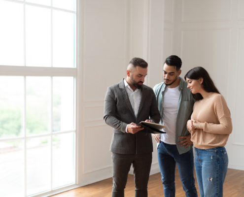 Couple Buying New Apartment, House Agent Showing Documents Blueprints
