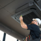Bearded Man Staying On Ladder Installing Air Conditioner At The Office