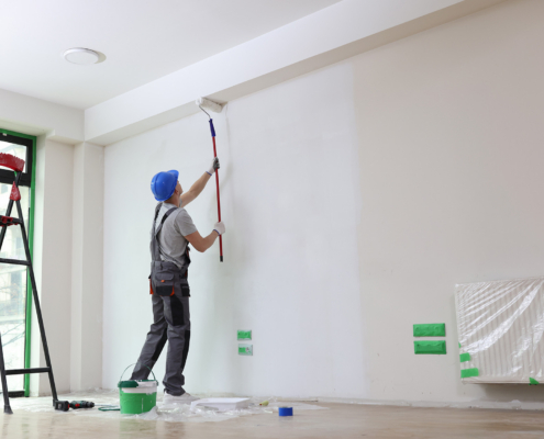 Worker Painting Walls In Home